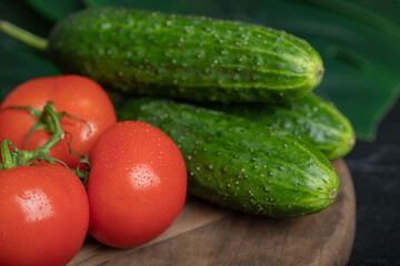 Close up photo of fresh tomato and cucumber on wooden board
