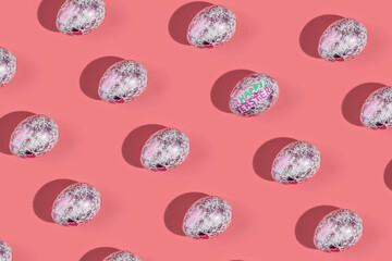 A pattern of shiny fashionable eggs on a pink background. Concept of Easter