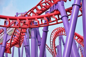 Roller coaster twisting rail track, blue sky with clouds background