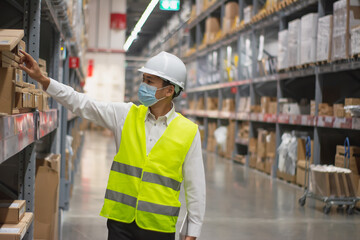 Soft focus asian engineer or technician wearing mask,safety hard hat,uses digital tablet check merchandise stock,security cargo management,in warehouse,industry business  logistic and export concept