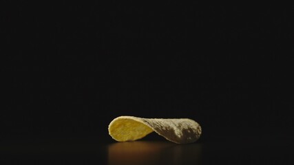Single potato chip on a black surface
