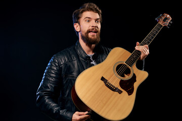 Obraz premium A man with a guitar in his hands leather jacket music performance rock star modern style dark background