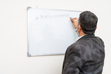 A man writing black lives matter on a white board. Teacher teaching about black lives matter.