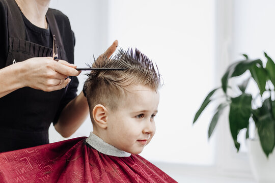 Close-up Of Woman Hands Grooming Kid Boy Hair In Barber Shop.