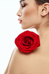 Naklejka premium Nude brunette woman with red flower on her shoulder and bright makeup
