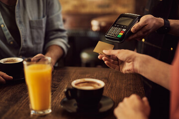 Close-up of woman paying with credit card in a cafe.