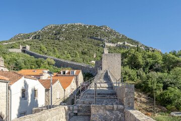 Fototapeta na wymiar Narrow stone passage stairs on Wall of Ston aong hills in Croatia summer sunny morning
