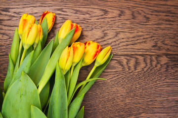 Bouquet of tulips resting on a table top; top view of yellow and red spring tulips