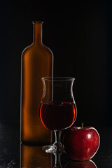 Eempty bottle of red wine, a glass of wine and an apple