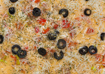 Raw omelet in a round frying pan, top view. Eggs, milk, cheese, olives, tomatoes, spices. Ready for further cooking. 