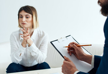 A woman on the sofa of a psychologist at the reception and a man with documents