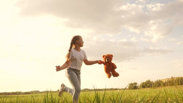 little girl with a teddy bear run in the park on the grass. happy family kid dream concept. little girl run in the park holding fun a teddy bear. happy childhood dream. kid walk in the park
