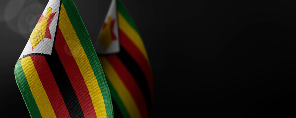 Small national flags of the Zimbabwe on a dark background