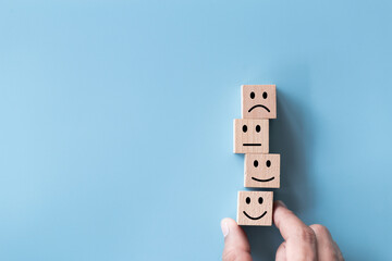 Close up top view customer hand choose smiley face on wood cube, Service rating, satisfaction...