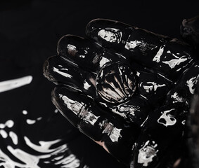 A hand in oil holds a silver coin. Symbol of oil business. Selective focus. Shallow depth of field.
