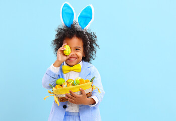 Funny little black child covering eye with Easter egg and smiling