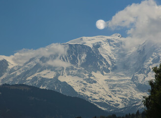Haute-Savoie, beautiful clouds over Mont Blanc peak and full moon on a sunny winter day French Alps. Europe, France.