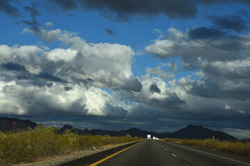 Driving on the highway towards the mountain in the horizon with rain clouds in the sky. Cumulostratus clouds. Nimbostratus clouds.