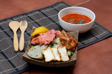 Dry Yentafo Tom Yum Noodles. Kuay Teow Shianghai Yen Ta Fo Tom Yum. Placed on a wooden plate with natural pattern coconut. Served with spicy and mellow soup. wooden spoons and forks on the small mat.