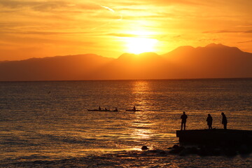 Naklejka na ściany i meble 片瀬江ノ島海岸から見る伊豆半島に沈むオレンジ色の夕日と堤防のシルエット