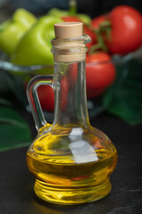 Bottle of olive oil in front of fresh vegetables
