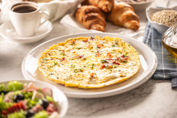 Fresh omelette served on a plate sprinkled with chopped chilli and cilantro, served along with assortment of breakfast food and coffee