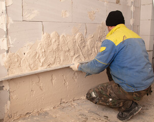 A worker plasters the walls in the room.