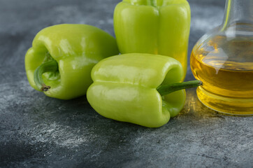 Close up photo of Fresh organic peppers with bottle of oil over grey background