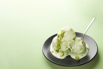 Melted balls of pistachio ice cream in a plate with copy space