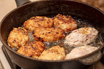 Minced beef cutlets are fried in a pan.