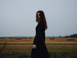 Beautiful woman in black dress red hair fresh air field nature model
