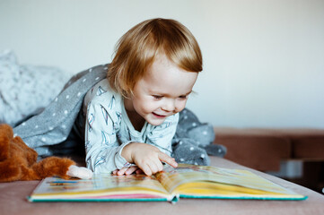 Cute little boy with enthusiasm reads the book. The child likes to read.