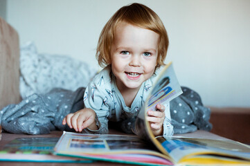 Cute little boy with enthusiasm reads the book. The child likes to read.