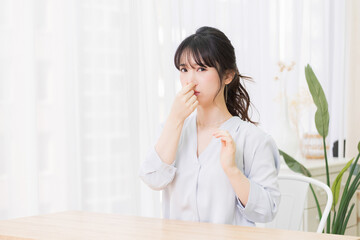 Fototapeta premium 部屋で鼻をつまむ若い女性