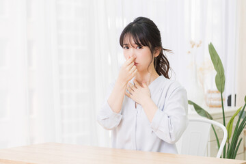 Fototapeta premium 部屋で鼻をつまむ若い女性