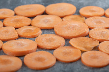 Close up photo of fresh carrot slices on grey background