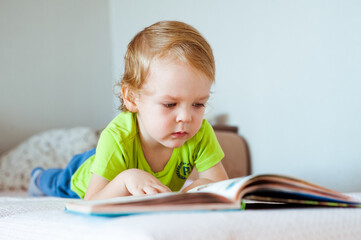 A small child enthusiastically reading a book. A love of books