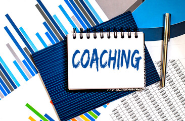 Paper with Coaching on table with charts and pen, business