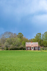 Old abandoned country cottage with dark clouds in the sky