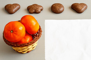 Tangerines in a basket and next to gingerbread cookies with a white sheet on a light background.