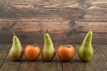 Delicious fuyu persimmons and ripe pears on wooden surface