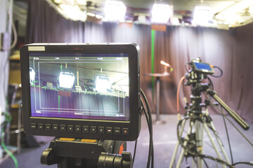 Professional film camera on tripod, broadcasting studio, spotlights and other recording equipment