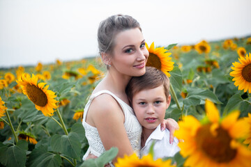 Happy mother with son having fun in the sunflowers field