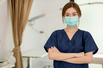 Fototapeta na wymiar Beauty clinic worker wearing hygiene mask and stand with arm-crossed in workplace area. Beauty business for good appearance to people during covid-19 pandemic concept.