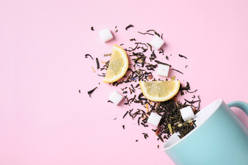 Flat lay composition with overturned cup and dry tea leaves on pink background