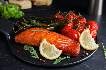 Delicious cooked salmon and vegetables on black table, closeup. Healthy meals from air fryer
