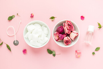 DIY concept. Wax, wick, dry roses - ingredients for making handmade candles on a pink background. Flat lay. View from above.
