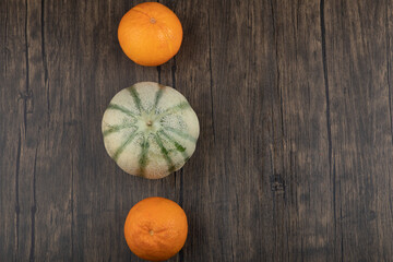 Whole healthy orange fruits with gray pumpkin on wooden table