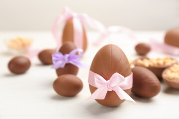 Sweet chocolate eggs on white wooden table. Space for text