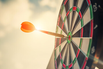Close up shot of the dart arrow hit on bulleyes of dartboard to represent that the business reached...